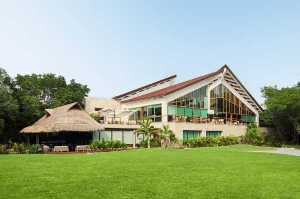 golf clubhouse overlooks lush green lawn with jungle landscape